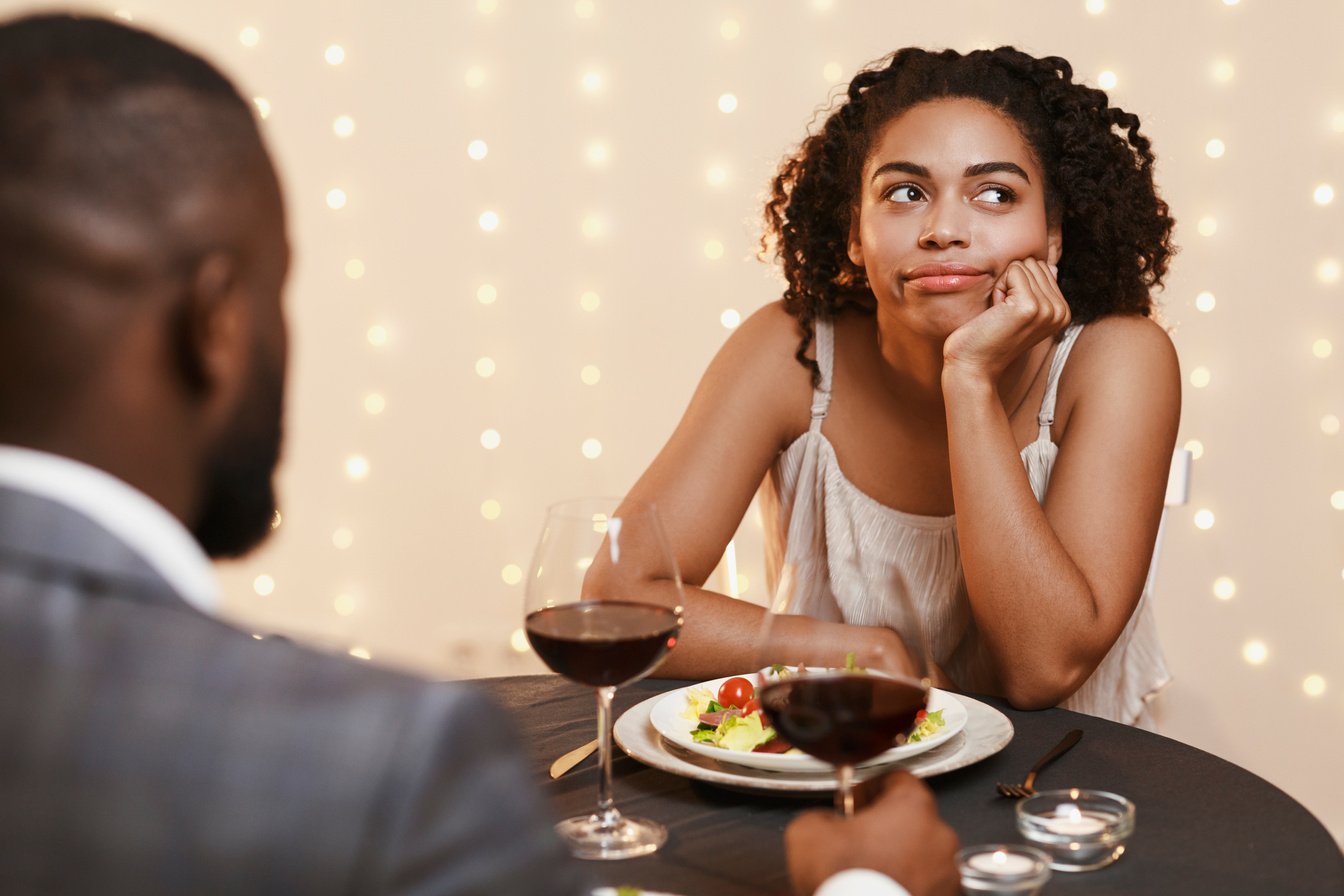 Bored afro woman attending first date at restaurant